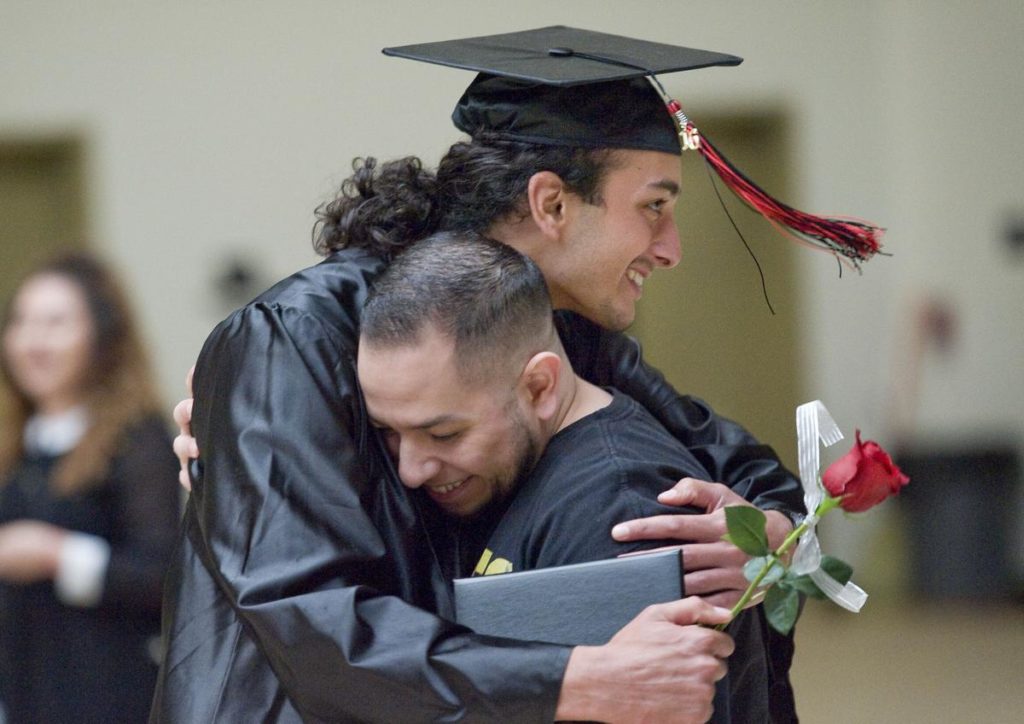 Graduate Christian Piccuito, top, from the Village of Hope at the Orange County Rescue Mission gets a hug after receiving his diploma from the Tustin Adult School on Tuesday. ///ADDITIONAL INFO: 0616.homelessghsgraduation - 6/7/16 - Photo by PAUL RODRIGUEZ - Twenty-six adults from Orange County Rescue Mission's Village of Hope graduate with their high school diploma from Tustin Adult School on Tuesday.